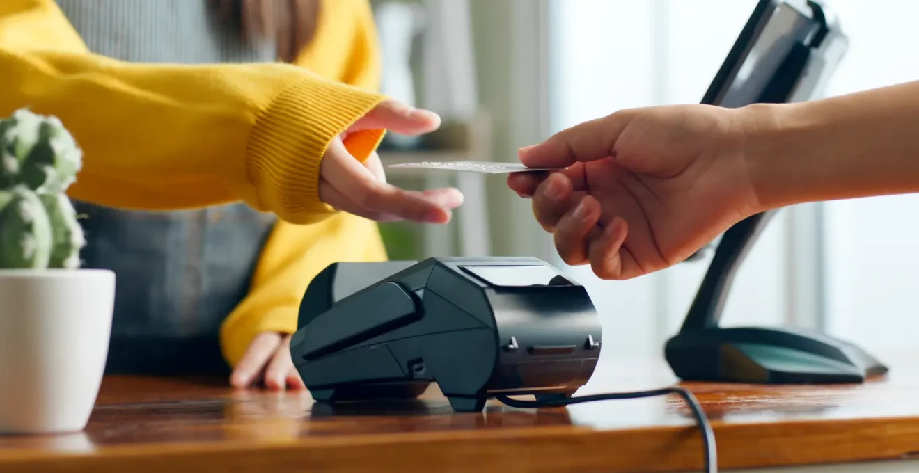 Un commerçant branche un terminal de paiement sur le comptoir de sa boutique.
